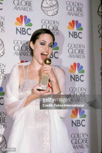 American actress Angelina Jolie licks her Golden Globe award for Best Performance by an Actress in a Supporting Role in a Series, Mini-Series or...