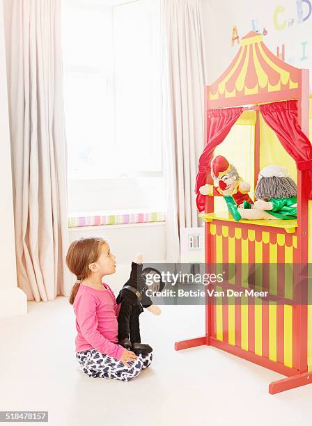 young girl watches punch and judy puppet show. - puppet show stock pictures, royalty-free photos & images