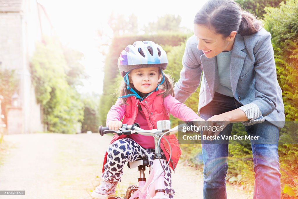 Mother is teaching her daughter cycling.