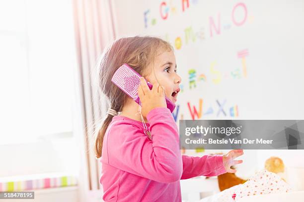 young girl is talking on toy mobile phone. - toy phones for kids stock pictures, royalty-free photos & images