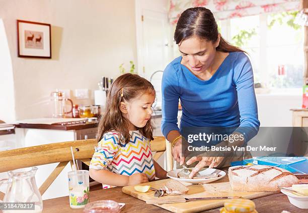 mother prepares sandwiches, daughter looks on. - making a sandwich stock pictures, royalty-free photos & images