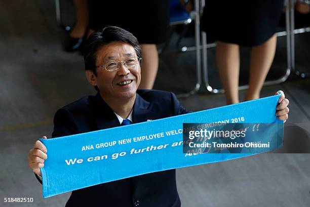 Holdings Inc. President and Chief Executive Officer Shinya Katanozaka holds up a banner for a group photograph during the welcome ceremony for newly...