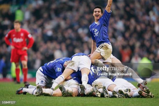 Tim Cahill of Everton celebrates as the Everton tean pile on top of goal scorer Lee Carsley during the Barclays Premiership match between Everton and...