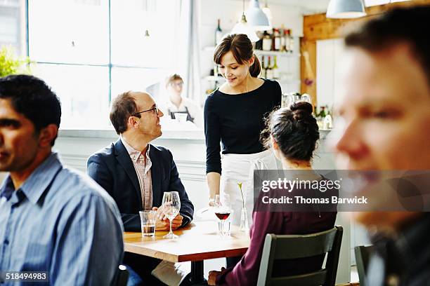 smiling waitress delivering check to couple - kellner oder kellnerin stock-fotos und bilder