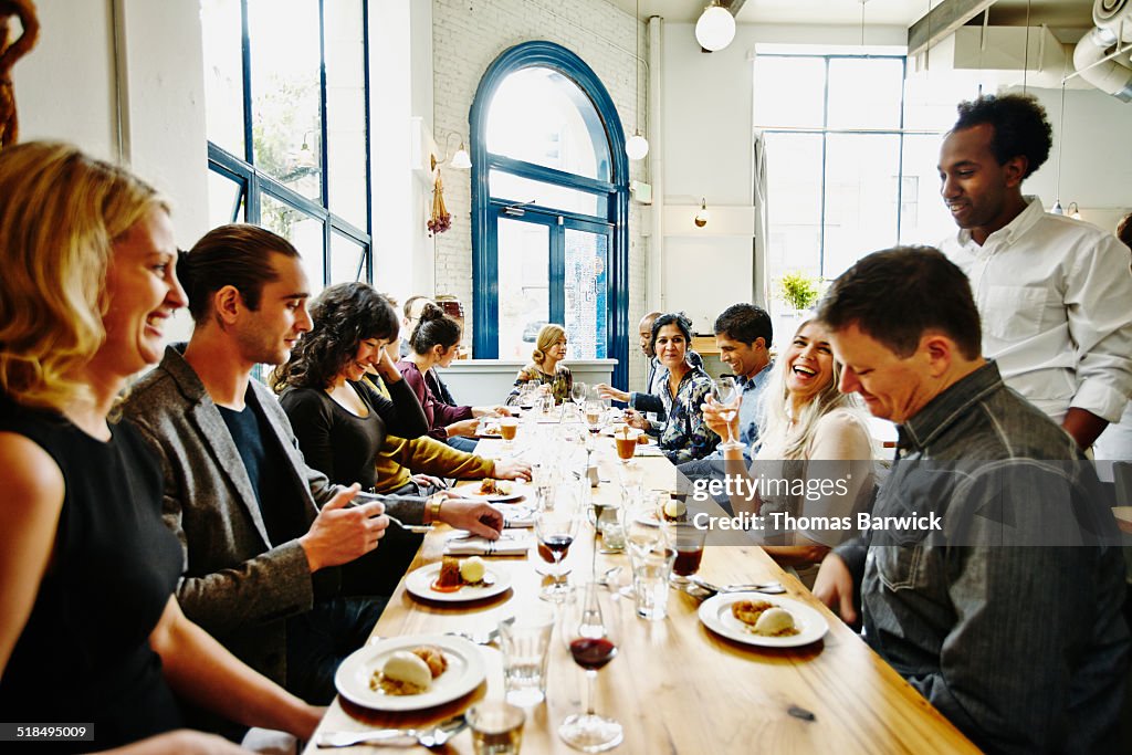 Laughing friends in restaurant eating dessert