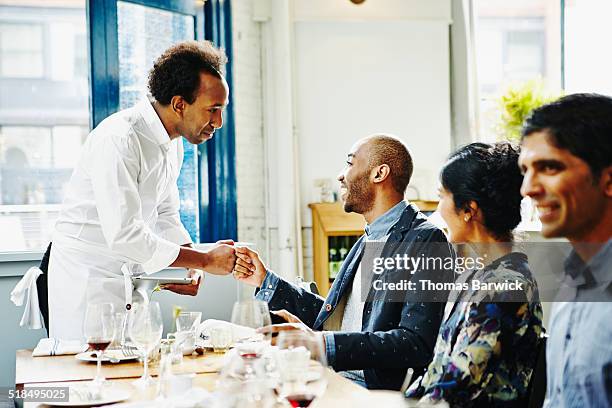 man sitting at table giving fist bump to waiter - customer appreciation stock pictures, royalty-free photos & images