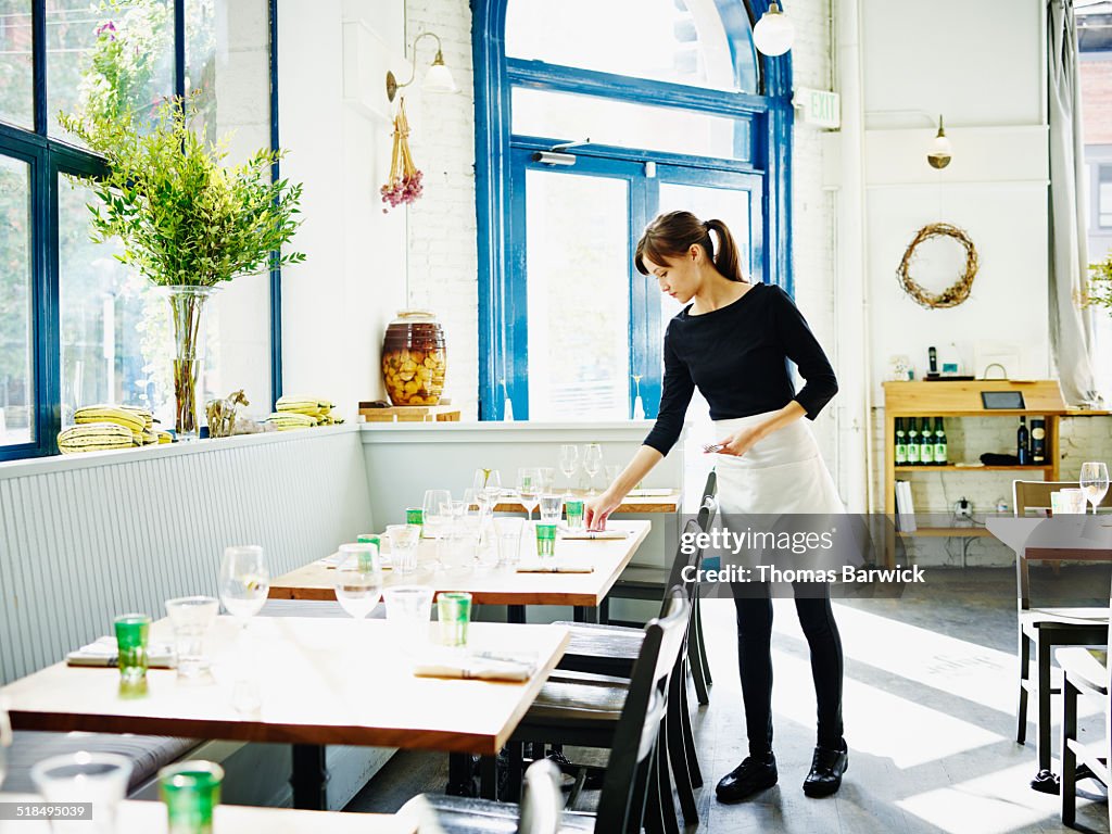 Waitress setting table in restaurant