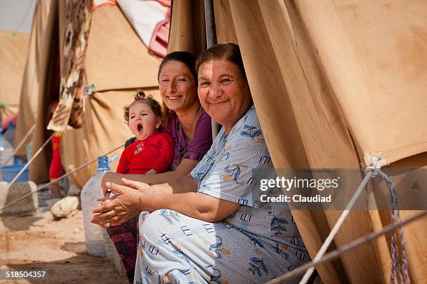 refugees in front of their tent - refugee tents stock pictures, royalty-free photos & images