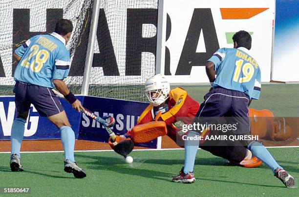 Pakistani field hockey goalkeeper Salman Akbar saves a goal attempt by Indian players Ignace Tirkey and Tushar Khandker during their men's Champions...