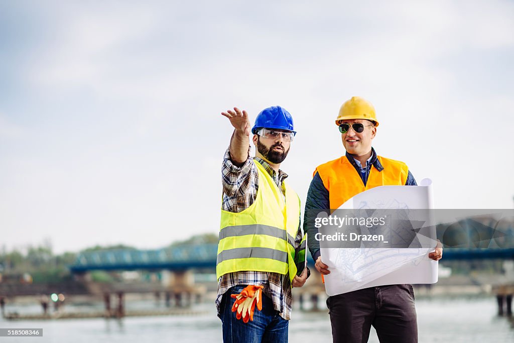 Engineers on bridge building site discussing next implementation phase
