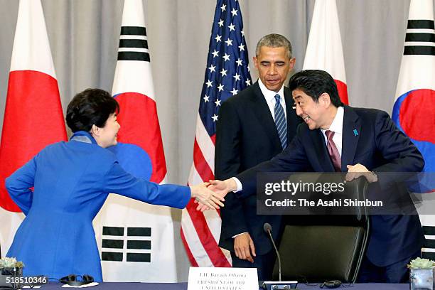 Japanese Prime Minister Shinzo Abe greets South Korean President Park Geun-Hye as U.S. President Barack Obama looks on during a meeting at the...