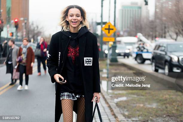 American model Binx Walton wears a black streetwear jacket with graphics, a pleated schoolgirl skirt, and fishnet tights after the Coach show during...