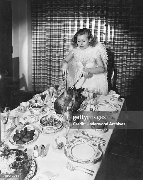 Fox actress Lillian Harvey carves the turkey for a Thanksgiving dinner, Hollywood, California, early 1930s.