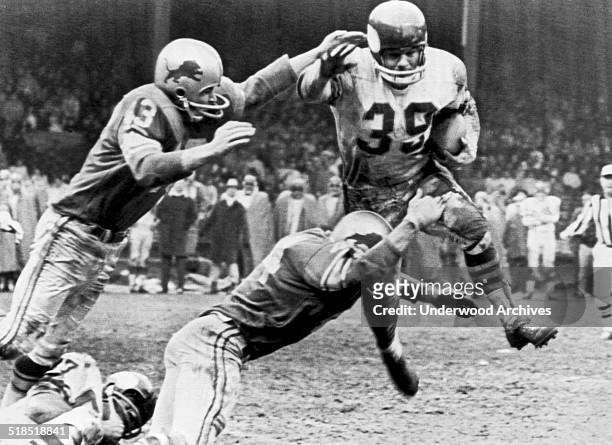 Minnesota Vikings running back Hugh McElhenny leaps but cannot avoid being tackled by Detroit Lions players, Gary Lowe and Dick LeBeau during a...