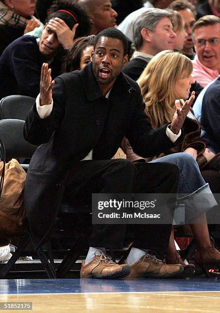 Comedian Chris Rock gestures to a fan as he takes in the New York Knicks vs Denver Nuggets game on December 12, 2004 at Madison Square Garden in New...