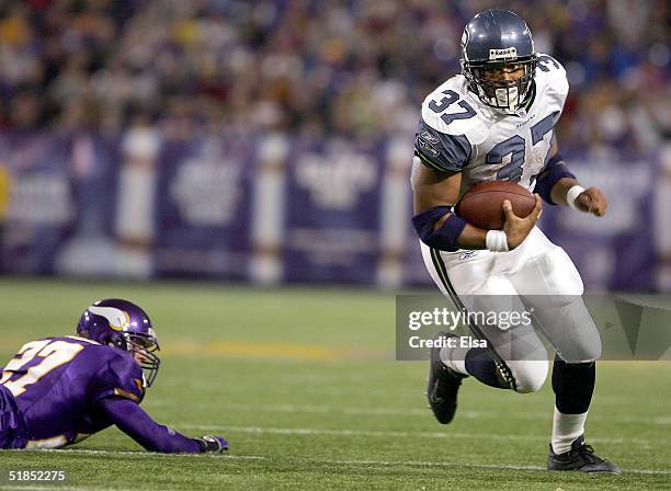 Shaun Alexander of the Seattle Seahawks runs past Brian Russell of the Minnesota Vikings on December 12, 2004 at the Hubert H. Humphrey Metrodome in...
