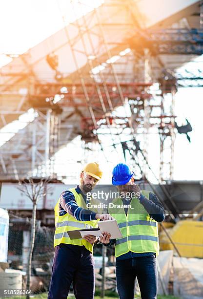 engineer and construction site manager dealing with blueprints and plans - bridge built structure stock pictures, royalty-free photos & images