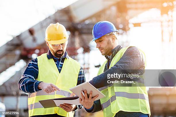 engineer and construction site manager dealing with blueprints and budget - bridge built structure stock pictures, royalty-free photos & images