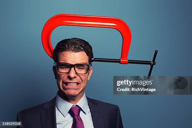 adult businessman in pain with vice on his head - clamp stock pictures, royalty-free photos & images