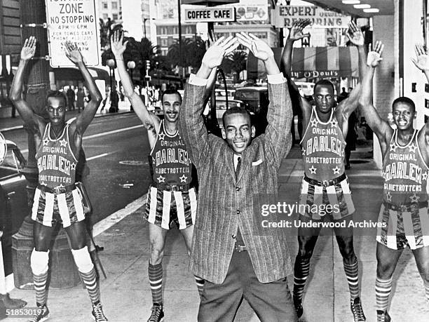 Chicago Cubs shortstop Ernie Banks leads members of the Harlem Globe Trotters in calisthenics on a downtown street, San Francisco, California,...