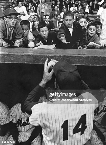 New York Mets first baseman Gil Hodges tantalizes young fans with the promise of an autographed baseball as they lean over the dugout on Gil Hodges...