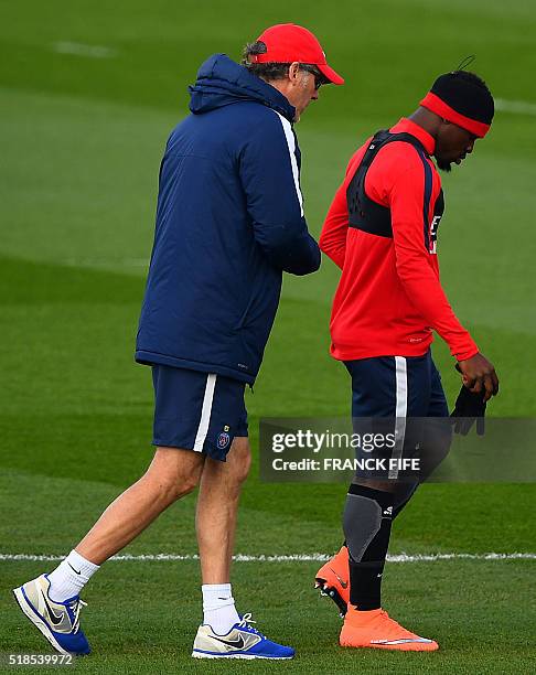 Paris Saint-Germain's French head coach Laurent Blanc speaks with Paris Saint-Germain's French defender Serge Aurier during a training session on...