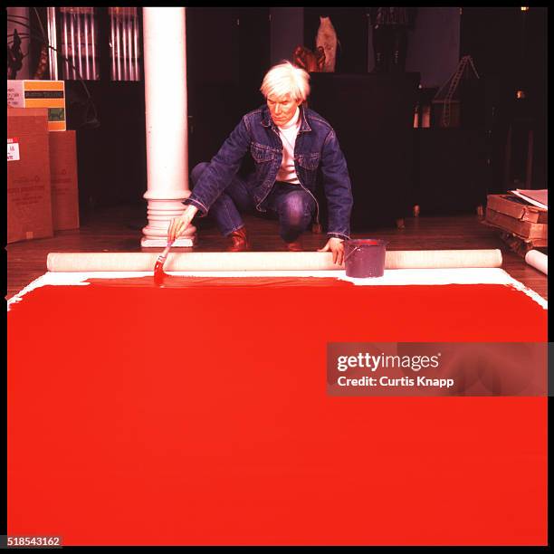 American Pop artist Andy Warhol paints a red canvas on the floor of his studio, the Factory, New York, New York, January 14, 1983.