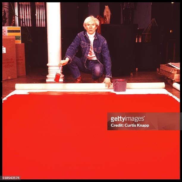 American Pop artist Andy Warhol paints a red canvas on the floor of his studio, the Factory, New York, New York, January 14, 1983.