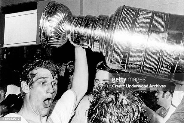 Boston Bruins star Bobby Orr whoops and holds up the Stanley Cup after he scored the winning goal in overtime against the St Louis Blues at the...
