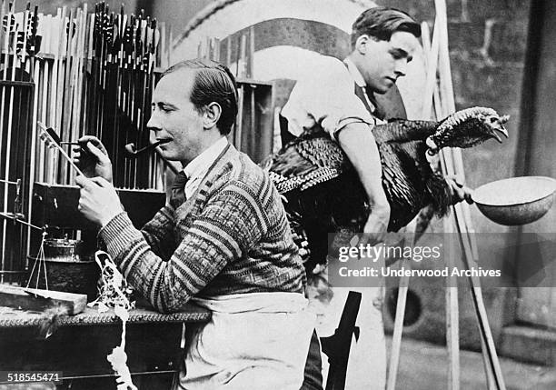 Albert Thompson carries on the 300 year old family business of manufacturing bows and arrows, Meriden, England, mid 1920s. He also raises turkeys to...