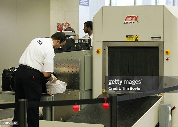 Transportation Security Administration worker checks baggage content, what turned out to be ice cream, after it passed through a CTX explosives...