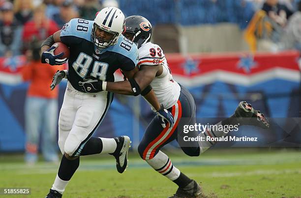 Tight end Erron Kinney of the Tennessee Titans is tackled by defensive end Adewale Ogunleye of the Chicago Bears during the game on November 14, 2004...