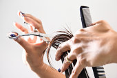 Hand with a comb cutting hair of woman