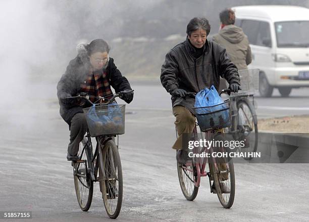 Cyclists make their way along a street in Beijing 14 December 2004, covered in heavy layer of thick smog and pollutants. China is now the world's...