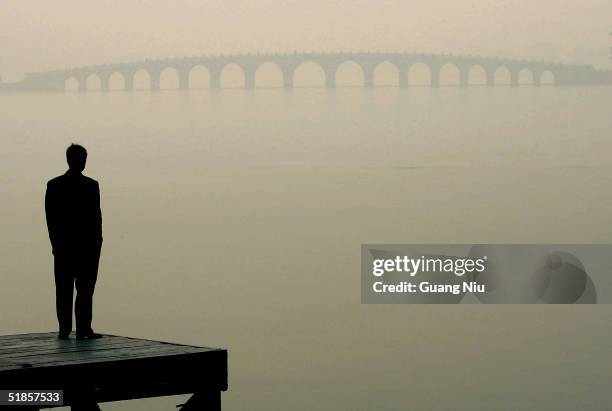 Man looks towards a bridge in heavy fog on December 14, 2004 in Beijing, China. The bad weather has made it harder for Beijing to achieve the target...