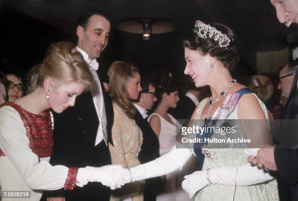 Queen Elizabeth II meets French actress Catherine Deneuve at a Royal film Performance, 14th March 1966. Also present are Christopher Lee, Ursula...
