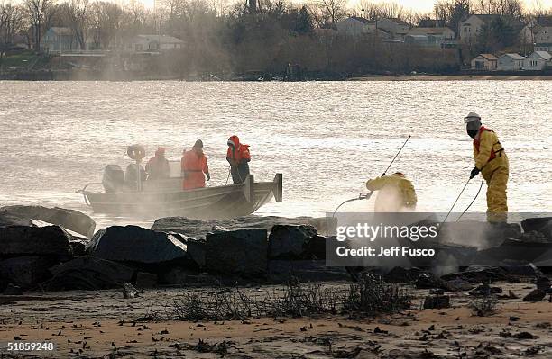 Environmental responders use pressurized hot water to clean oil from the shore of the Delaware River December 14, 2004 in Philadelphia, Pennsylvania....