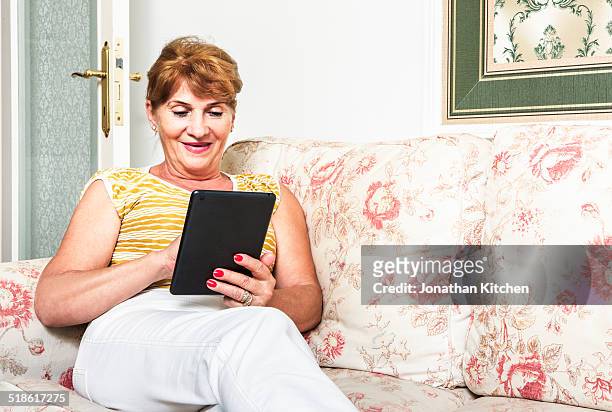 older lady using a tablet computer - floral pattern trousers stock pictures, royalty-free photos & images