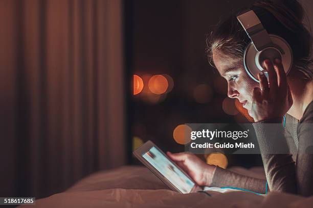 woman using tablet pc in evening. - mensch bett stock-fotos und bilder