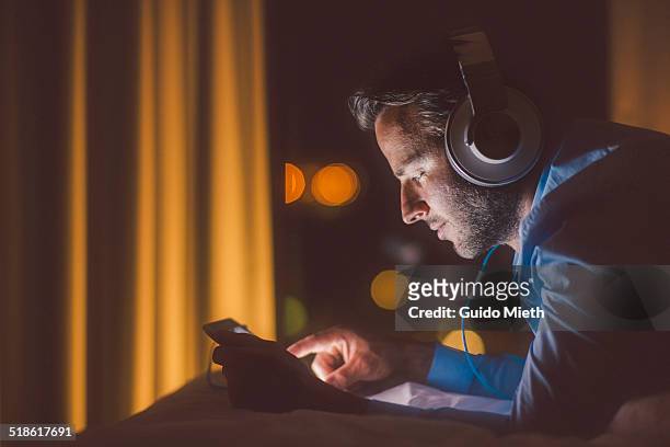 man using tablet pc in evening. - listening stock-fotos und bilder