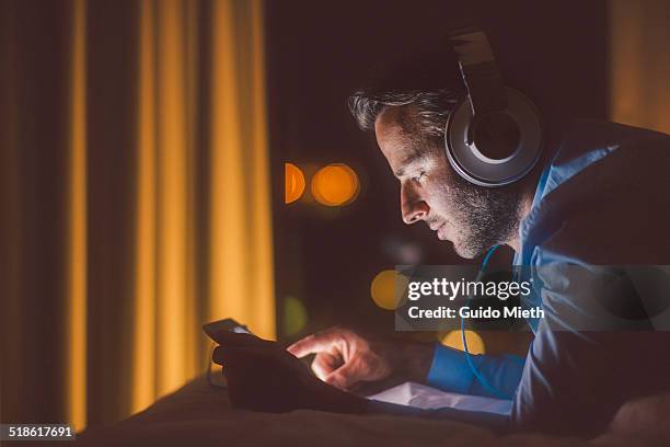 man using tablet pc in evening. - headphones fotografías e imágenes de stock