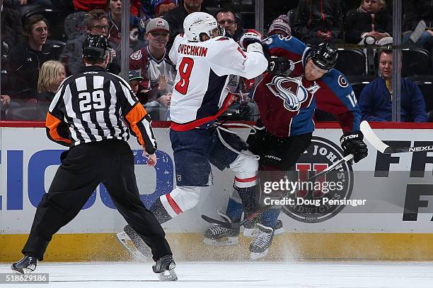 Alex Ovechkin of the Washington Capitals puts a hit on Jarome Iginla of the Colorado Avalanche as referee Ian Walsh oversees the action at Pepsi...