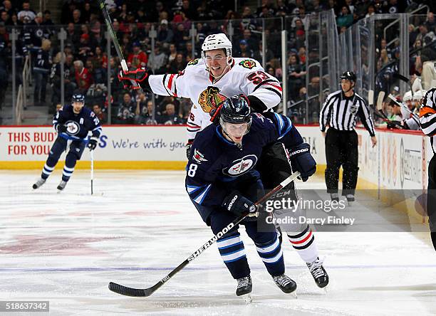 Brandon Mashinter of the Chicago Blackhawks and Jacob Trouba of the Winnipeg Jets battle for position as they follow the play down the ice during...