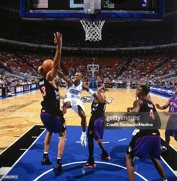 Steve Francis of the Orlando Magic looses the ball as he drives to the basket between Loren Woods and Vince Carter of the Toronto Raptors during a...