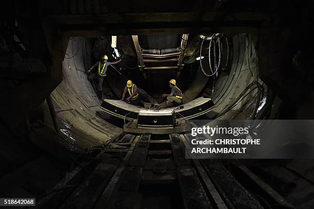 This picture taken on March 11, 2016 shows workers preparing curved concrete segments to be attached to form the inner surface of a tunnel being dug...