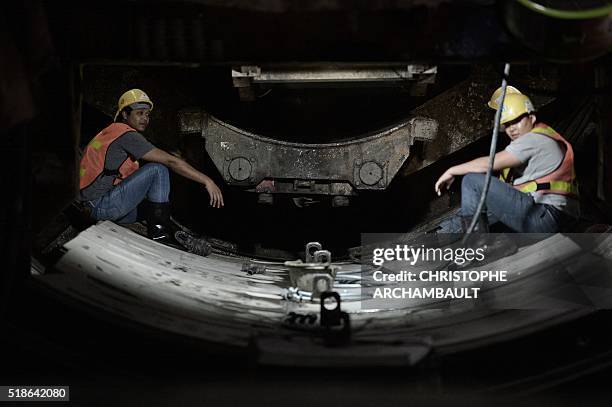 This picture taken on March 11, 2016 shows workers sitting on curved concrete segments to be attached to form the inner surface of a tunnel being dug...