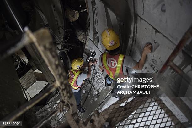 This picture taken on March 11, 2016 shows workers attaching together curved concrete segments to form the inner surface of a tunnel being dug by a...