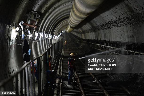 This picture taken on March 11, 2016 shows a worker using a hose as he clears soil from a tunnel under construction along the current extension of...