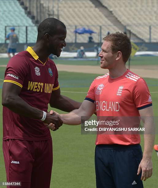 England's cricket team captain Eoin Morgan and West Indies captain Darren Sammy pose with the World T20 tournament trophy at the Eden Gardens cricket...