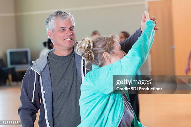 senior man dances with wife at senior center - line dancing stock pictures, royalty-free photos & images